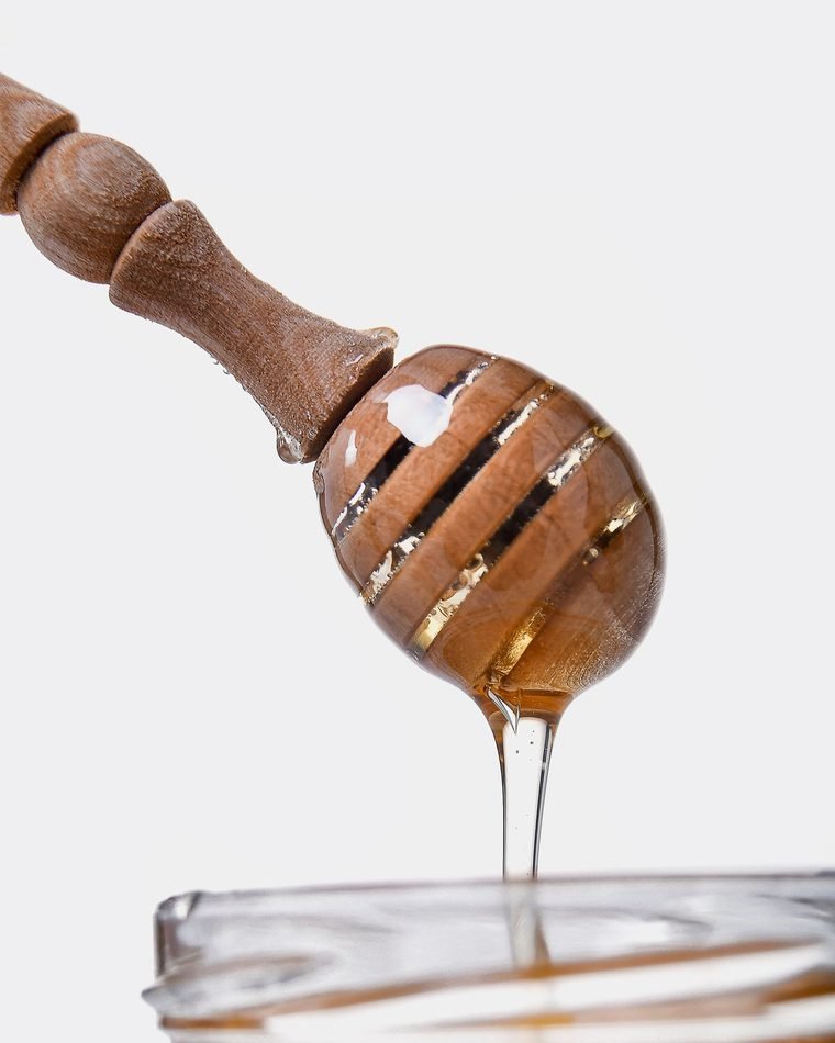 عسل طبيعي يسيل من ملعقة عسل خشبية